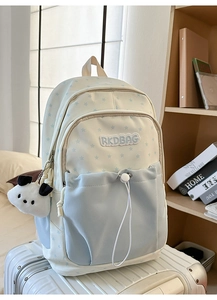 Detail of canvas school backpack featuring star patterns and a cute panda plush charm