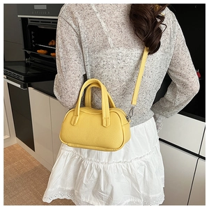 Sac à main tendance en cuir grainé jaune vif porté en bandoulière dans un décor moderne