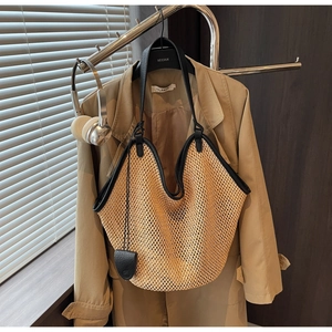 Détail du sac cabas en paille tissée avec anses en cuir noir sur un cintre de mode