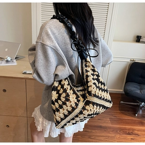 Close-up of geometric knit tote bag with black leather braided shoulder straps and bow