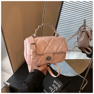 Detail of pink quilted crossbody bag featuring metal turn-lock and chain handle design