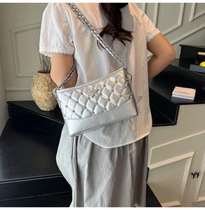 Detail of silver quilted crossbody bag with star studs and chain strap on a model