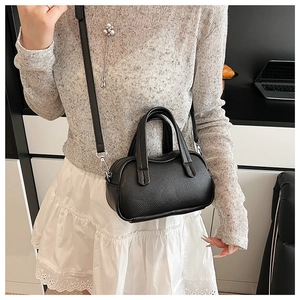 Détail du mini sac noir grainé avec bandoulière et finitions métalliques argentées