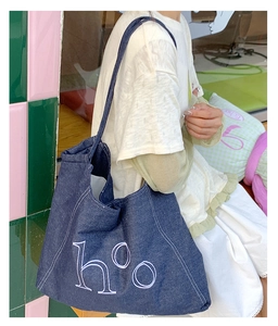 Detail of blue denim tote bag with white h°o embroidery and contrast stitching