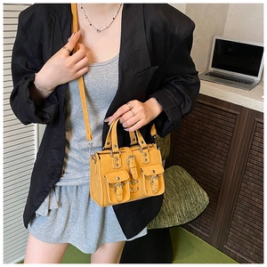 Detail of ginger yellow biker style mini handbag with utility pockets and silver hardware