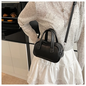Détail d'un mini sac Boston en cuir grainé noir avec doubles poignées et ferrures