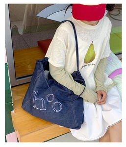 Detailed close-up of large blue denim tote bag with white h°o embroidery lettering
