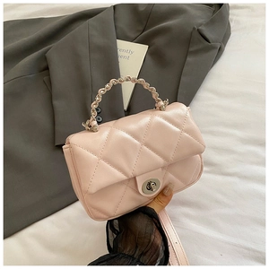 Detail of pink quilted crossbody bag featuring silver chain handle and metallic twist lock