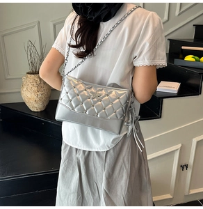 Detail of silver quilted underarm bag with metal star ornament and sparkling studs