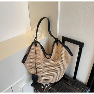 Détail du sac cabas en paille tressée avec poignées en cuir noir et bandoulière