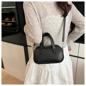 Détail d'un sac à main noir grainé avec des finitions argentées dans un cadre de vie