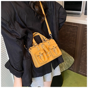 Detail of yellow biker style faux leather crossbody bag with multiple utility pockets