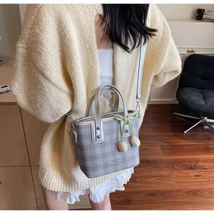 Detail of grey plaid handbag with tulip charm and adjustable crossbody strap