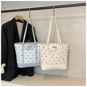 Detail of floral tote bags in light blue and beige with red bow patterns and heart charms