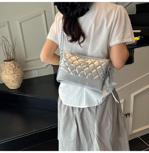 Detail of silver quilted bucket bag with star rivets and chain strap on a model