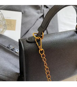 Detail of black lychee grain leather handbag with shiny gold metal chain and hardware