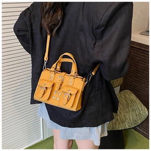 Detail of yellow retro biker bag with studs and buckle pockets on a model shoulder
