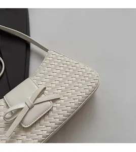 Détail du motif tressé en similicuir et du nœud élégant sur le sac à bandoulière crème