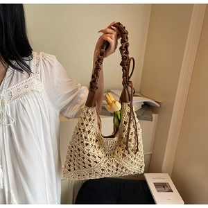 Detail of hollow-out straw handbag with brown pleated leather handle and bow knot
