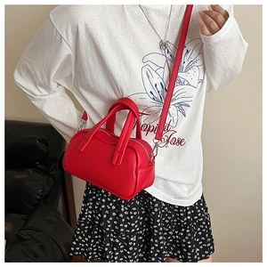 Détail du sac Boston en cuir rouge grainé avec zip argenté et bandoulière amovible