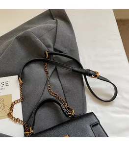 Detail of black crossgrain leather texture with adjustable strap and vintage gold chain
