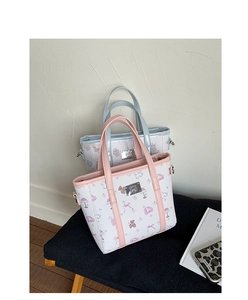 Close-up of cute cartoon bear prints and silver logo on pink and blue tote bags