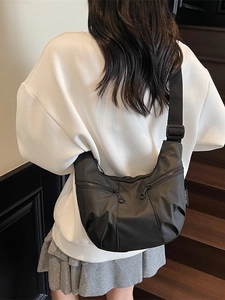Black crescent crossbody bag with dual zippers and adjustable wide strap on model