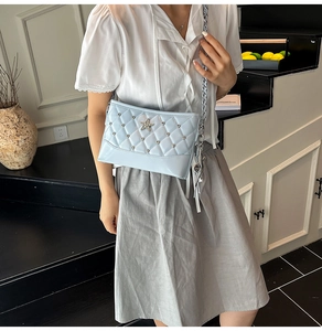 Detail of light blue quilted chain bag with crystal star stud and tassel on a model