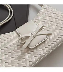 Détail macro du cuir tressé beige et du nœud en relief sur ce sac baguette de style chic