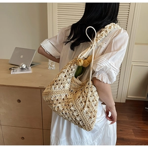 Detail of hand-woven straw shoulder bag featuring pleated cloud straps and tulip accent