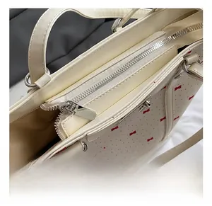 Detail of silver metal zipper and D-ring on floral tote bag with red bow pattern