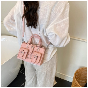 Pink punk-style Boston bag with silver studs and buckles worn by a model