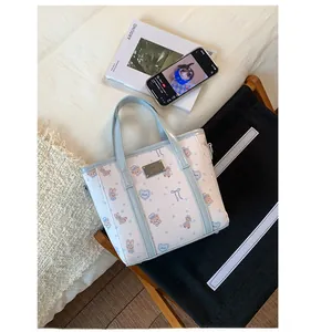 Close-up of white bucket bag with cute cartoon bear prints and metal logo plaque