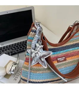 Détail d'un sac en paille tressée à rayures colorées avec bandoulière en cuir et breloque