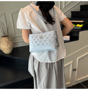 Detail showing quilted light blue patent leather bag with star ornament and silver chain