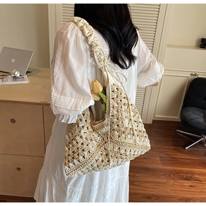 Detail of hand-woven straw tote bag with wide pleated shoulder strap and bow ribbon