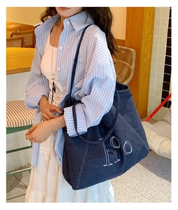Detailed close-up of dark denim tote bag featuring white embroidered ho lettering detail