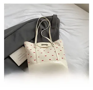 Detail of cream canvas tote with red bow print and silver metal clasp decoration