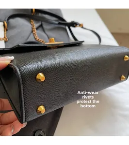 Detail of gold metal protective studs on the bottom of a black lychee leather handbag
