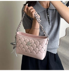 Detail of pink quilted shoulder bag with star charms and silver chain strap for women