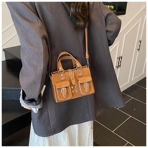 Brown vintage style handbag with silver buckles and flap pockets on a modern model