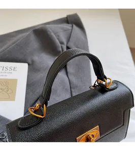 Detail of black pebbled leather handbag featuring gold heart-shaped connectors and twist lock