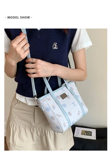 Detail shot of a cartoon patterned bucket bag with light blue leather straps and metal plaque