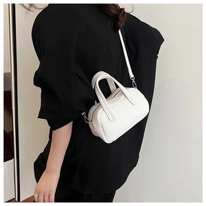 Gros plan du mini sac Boston en cuir blanc porté par un mannequin en chemise noire
