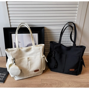 Close-up of canvas tote with front pockets and matching round zipper coin purse attachment