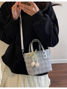 Grey checkered mini crossbody bag with silver trim and tulip charm on a female model