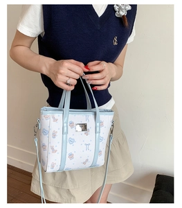 Detail of light blue crossbody bucket bag featuring cute cartoon animal print and handles