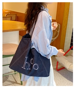 Close-up of a large capacity blue denim tote bag with white ho embroidered letters