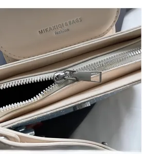 Detailed close-up of smooth silver zipper and embossed logo on beige PU leather bag