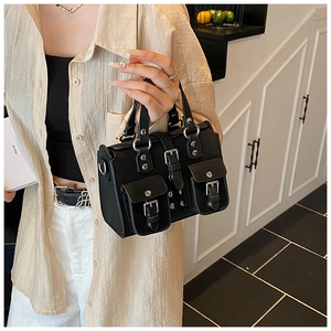Detail of a black vintage utility style handbag with metal buckles and silver hardware